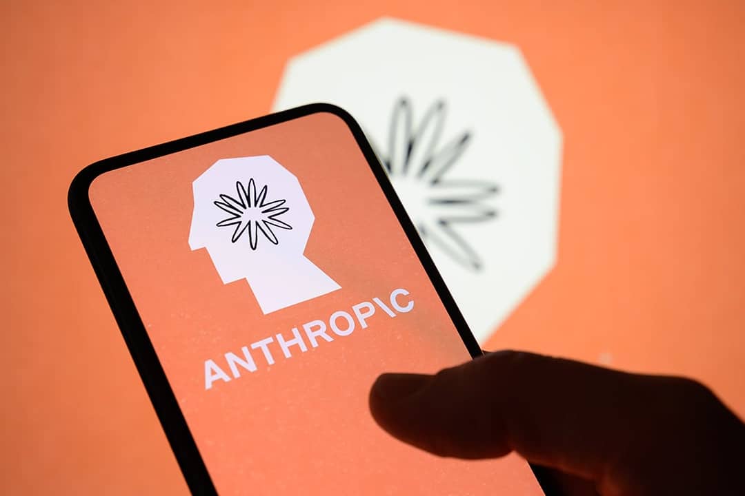 The Anthropic logo displayed from a smartphone's screen with the company's brand in the background.